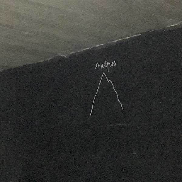 Photo d'un mur noir avec un dessin minimalist d'une montagne et le texte Aalpes